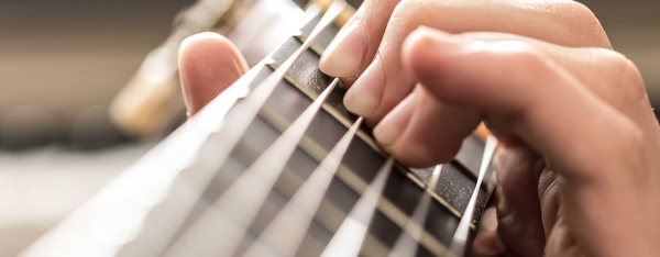 Greifhand am Griffbrett einer Gitarre