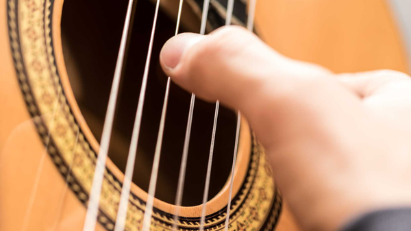 Spielhand am Schallloch einer Gitarre