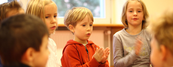 Kinder singen und klatschen im Stuhlkreis